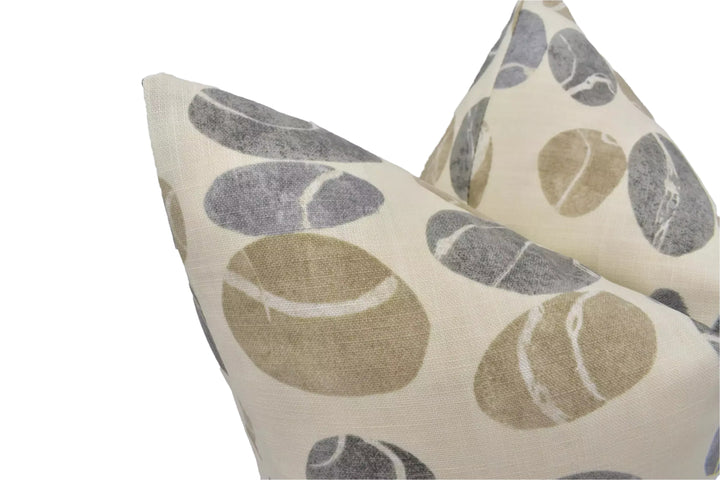 a close-up view of a beige and gray patterned pillow with a repeating design of large, round shapes.