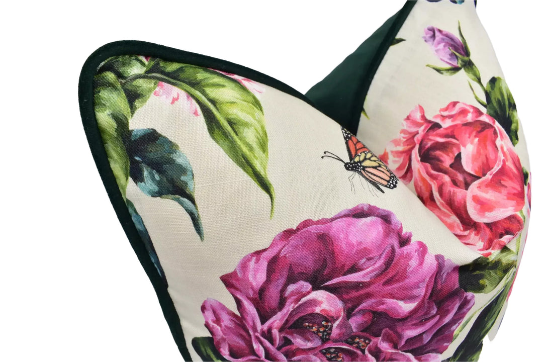 A close-up image of a decorative pillow with a floral pattern, featuring a large pink peony and a butterfly.
