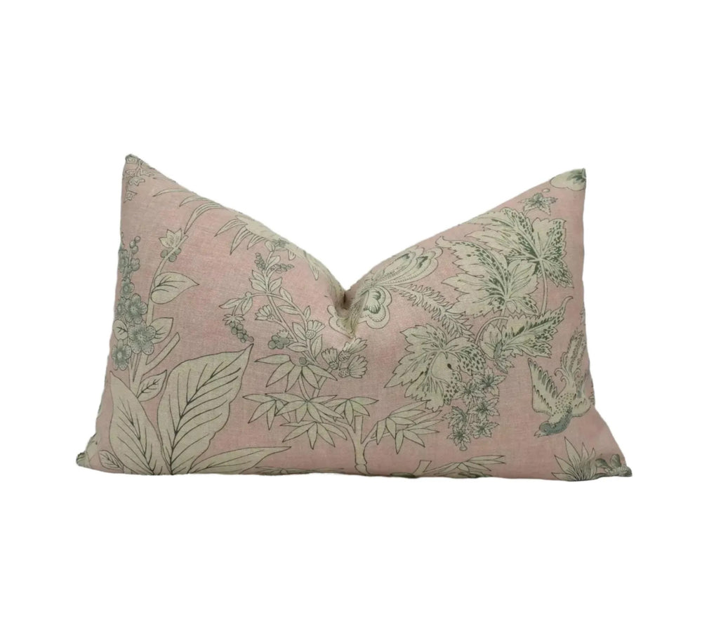 A pink and green floral patterned pillow against a white background.