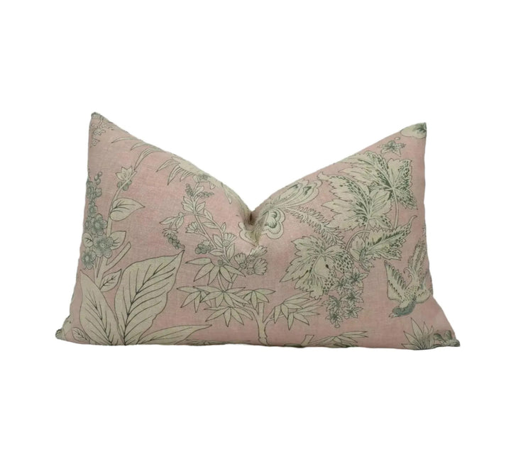 A pink and green floral patterned pillow against a white background.