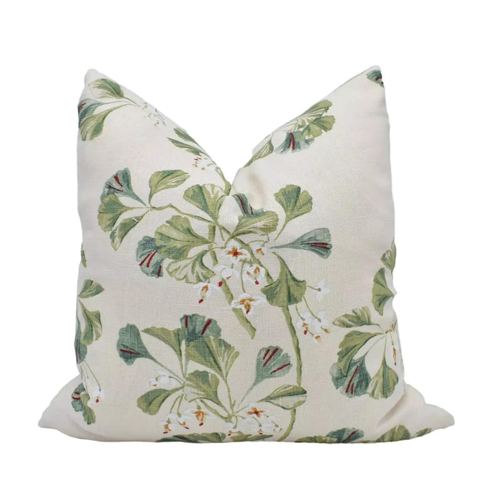 a white pillow with a floral print design featuring green leaves and white flowers.