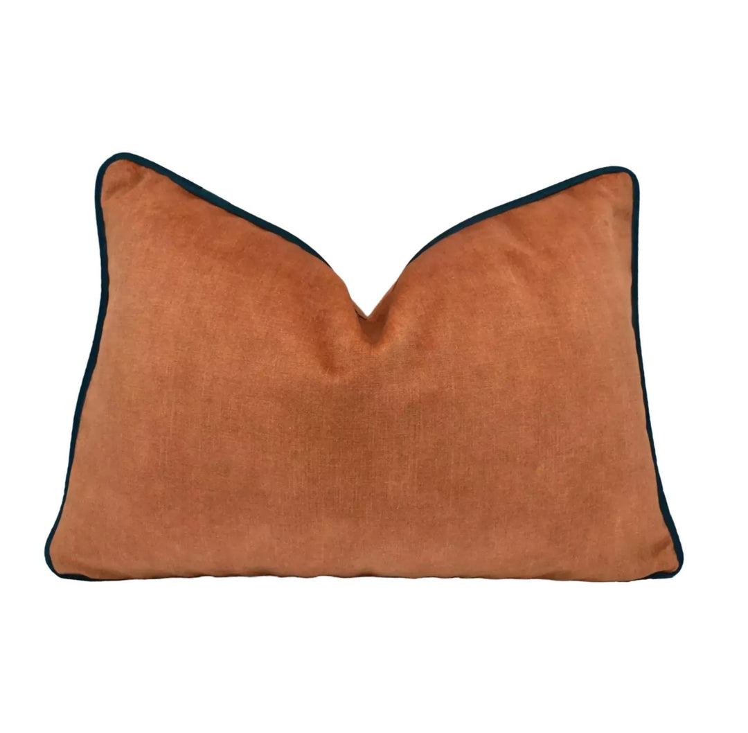 A single orange throw pillow with a teal broder