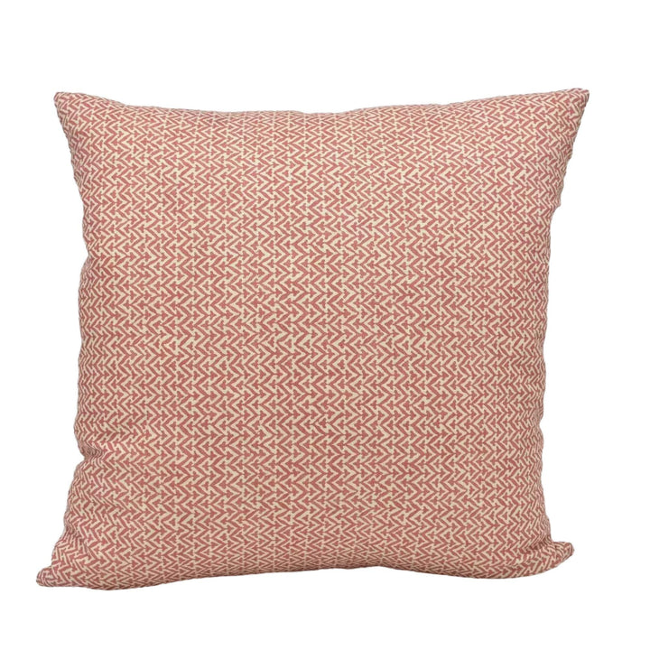 A square throw pillow with a repeating pattern of red and white geometric shapes.