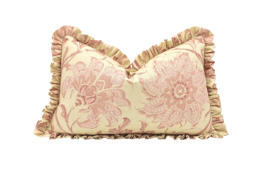 A decorative pillow with a floral pattern in shades of pink and yellow, featuring ruffled edges and a ruffled trim around the edges.