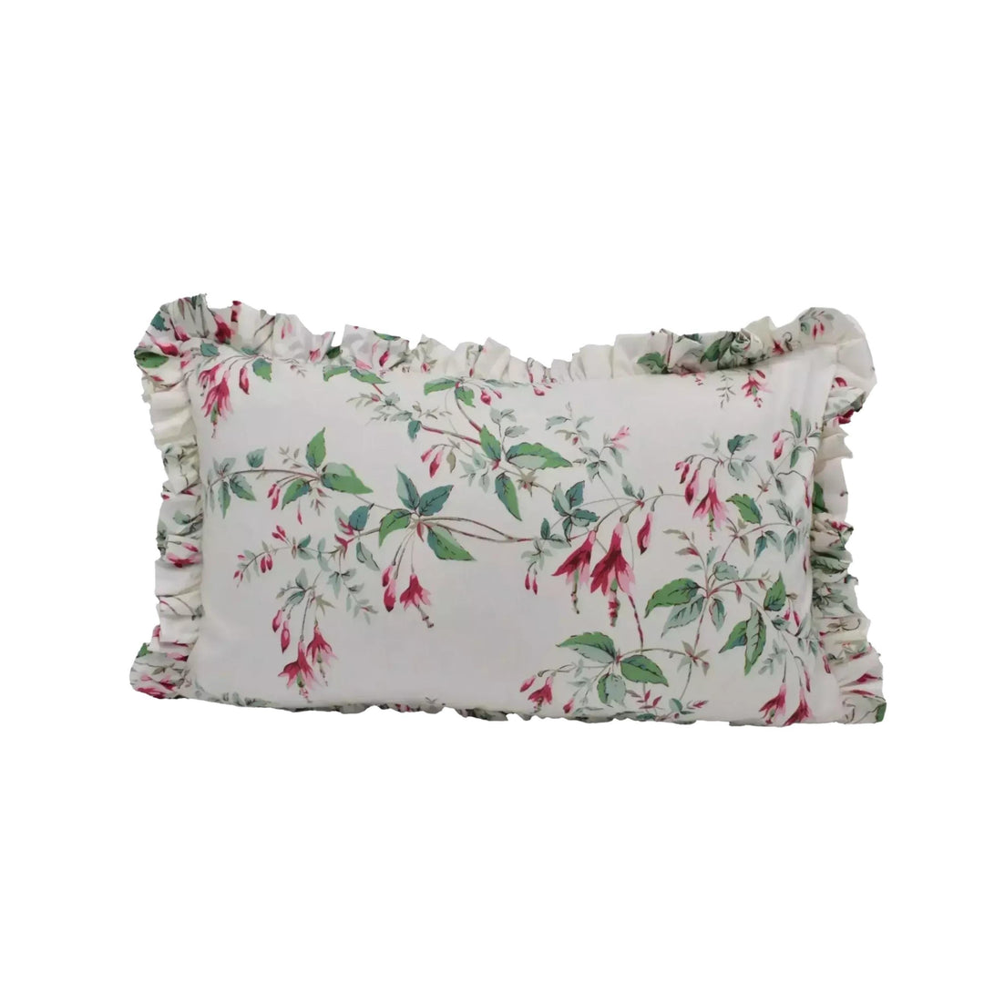 A white pillow with a floral print design, featuring green leaves and red flowers.