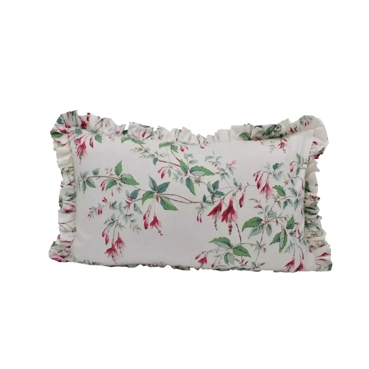 A white pillow with a floral print design, featuring green leaves and red flowers.