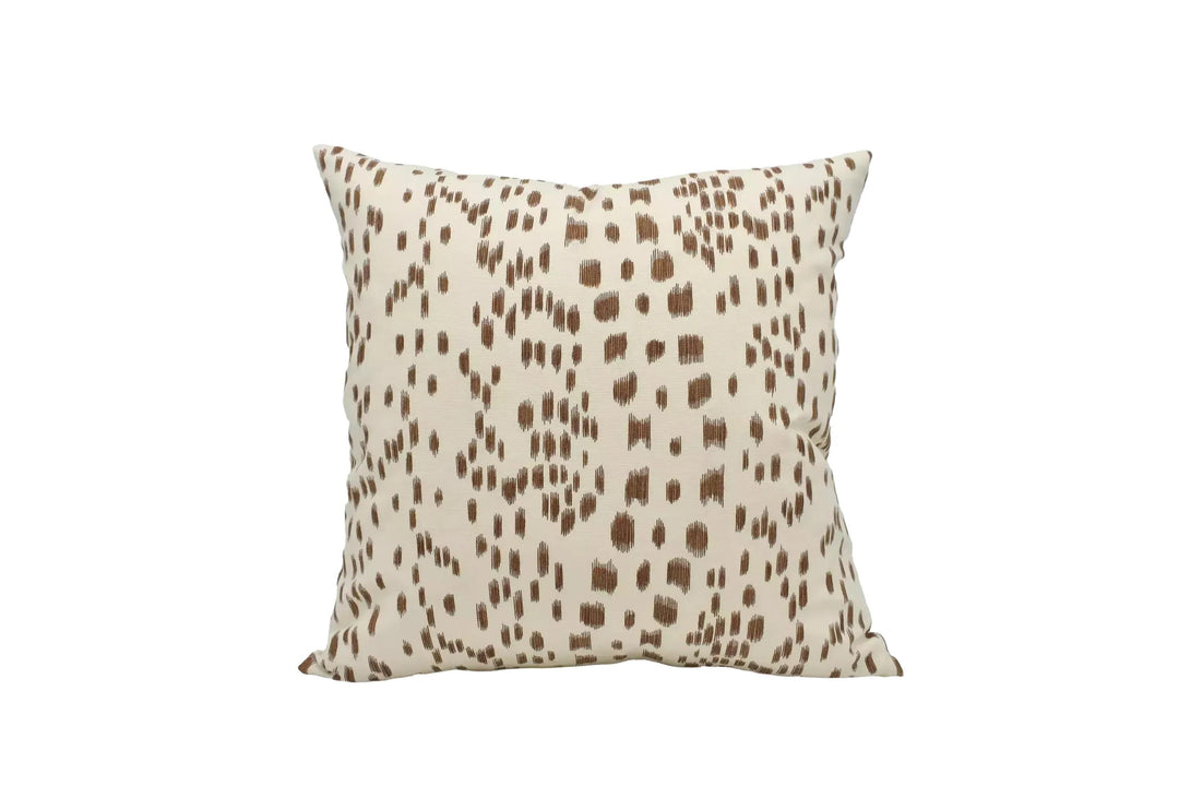A square throw pillow with a brown spotted pattern is displayed against a white background.