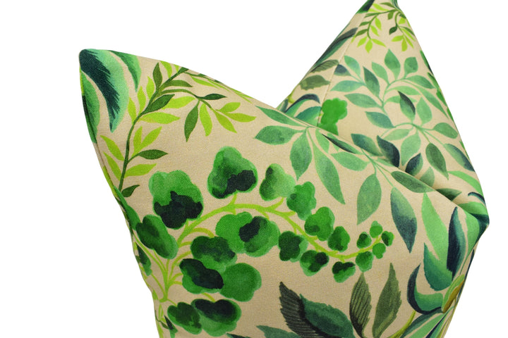 a close-up view of a decorative pillow with a leafy green and beige color scheme. The pillow has a pattern of green leaves and branches, creating a visually appealing and natural design.