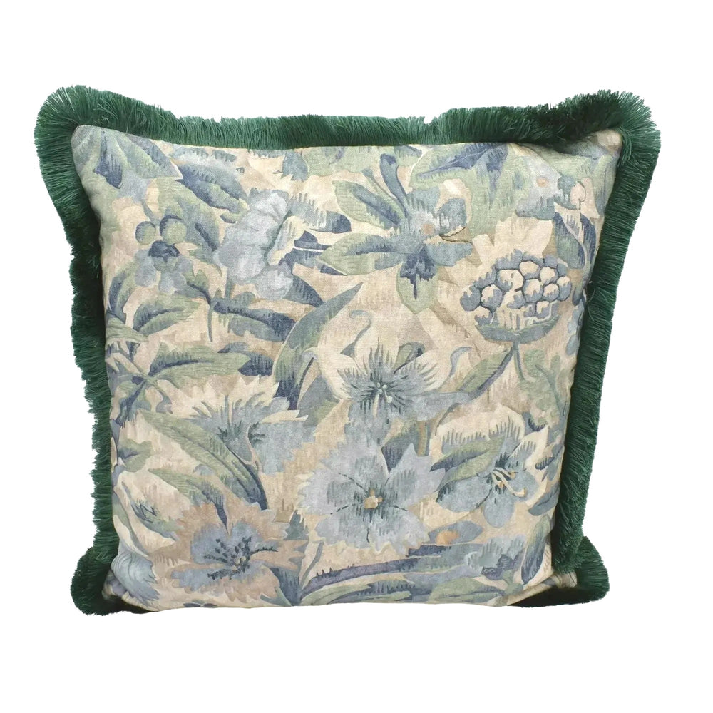A decorative throw pillow with a floral print and green fringe is displayed against a white background.