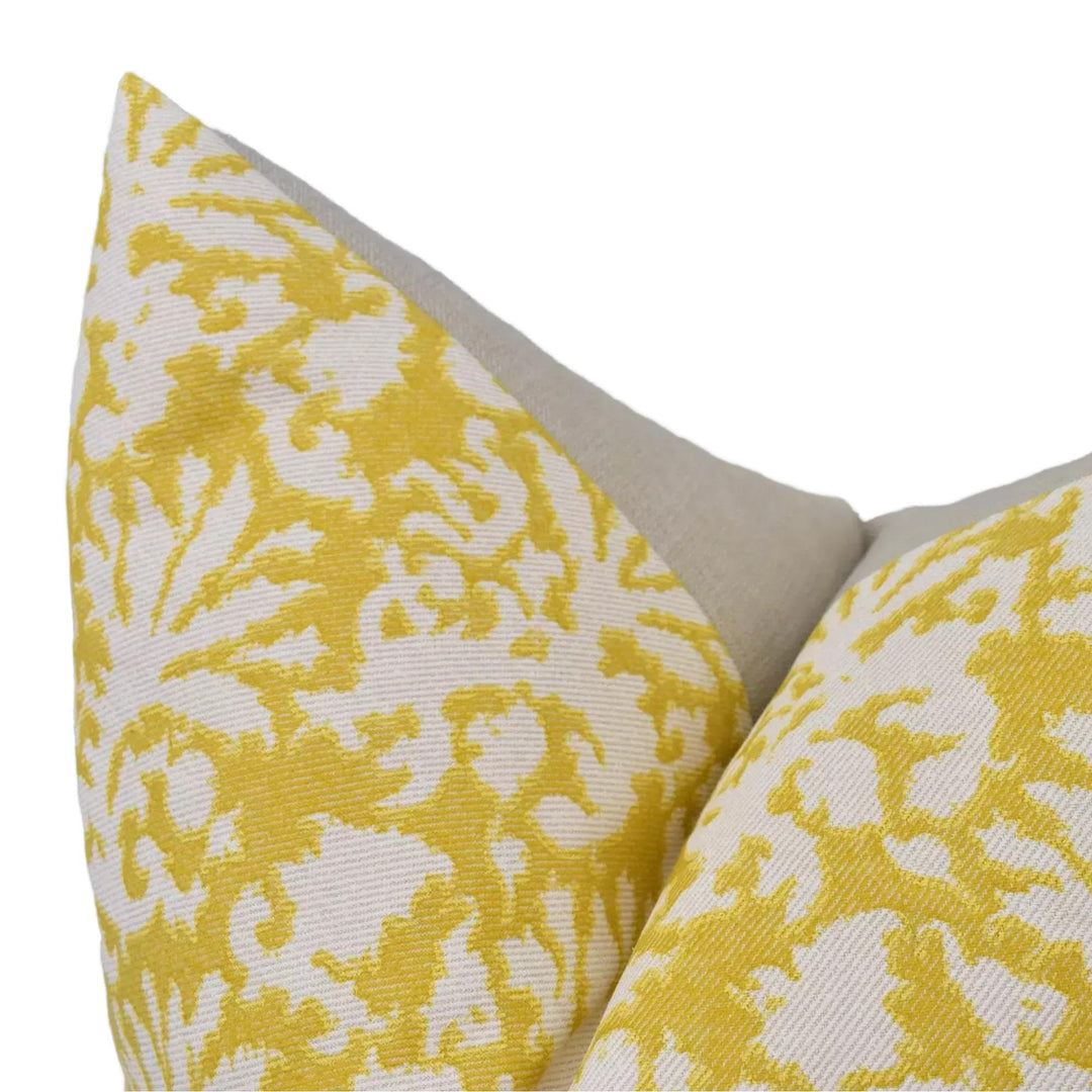 A close-up view of a yellow and white patterned pillow, with a beige fabric lining.