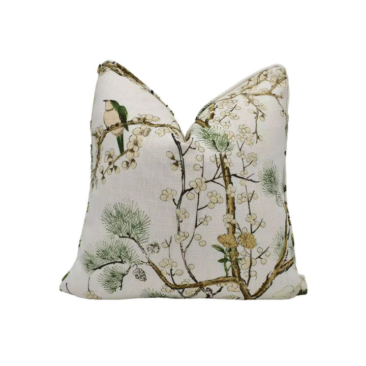 A white pillow with a floral print design featuring a bird perched on a branch with white flowers.