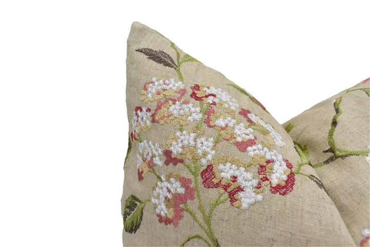 A close-up view of a beige fabric with a floral pattern, featuring white and red flowers and leaves.