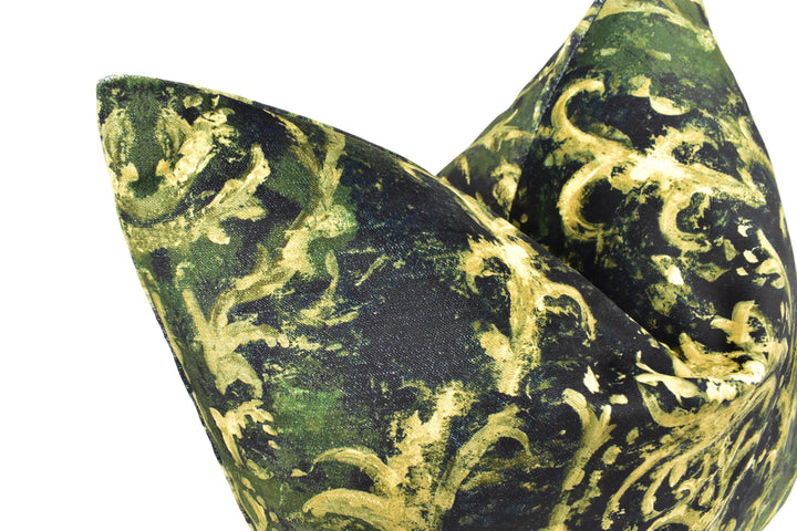 A close-up view of a green and black patterned fabric, possibly a pillow or cushion, with a gold-colored design.