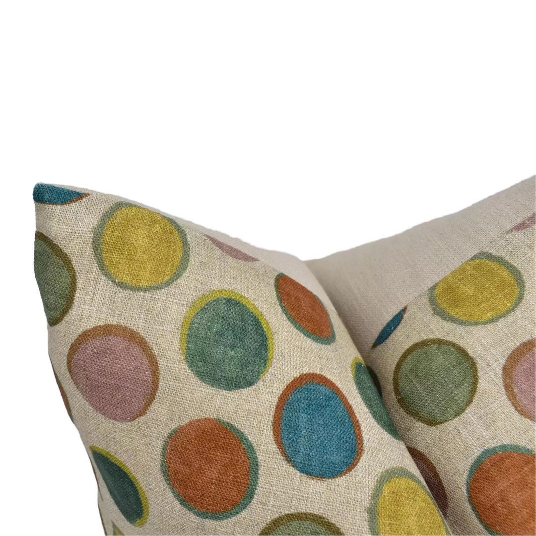a close-up view of a beige fabric with a colorful polka dot pattern, featuring a variety of circular shapes in different colors such as yellow, green, orange, and blue.