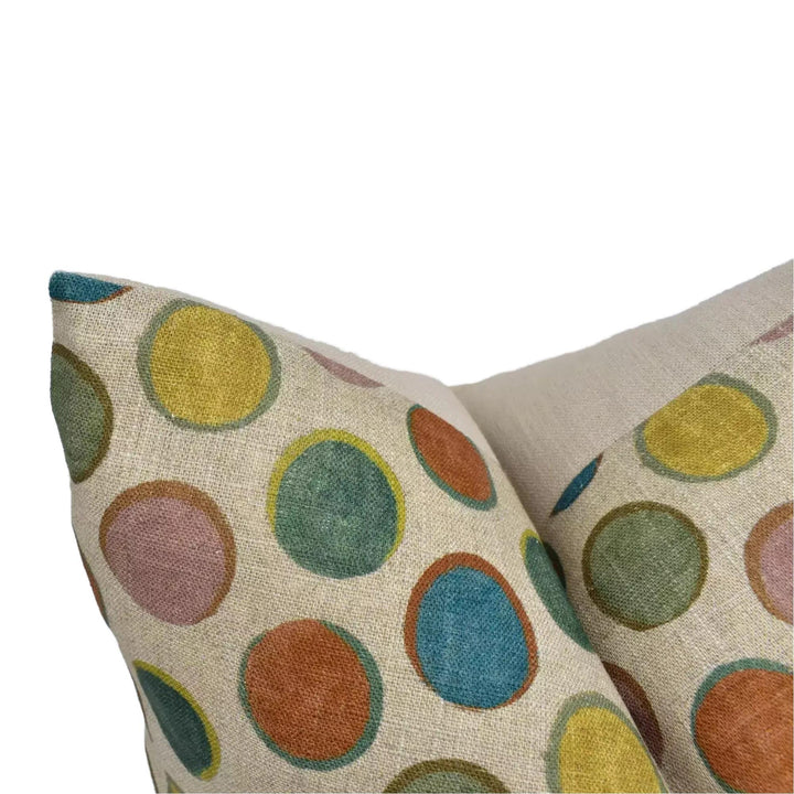 a close-up view of a beige fabric with a colorful polka dot pattern, featuring a variety of circular shapes in different colors such as yellow, green, orange, and blue.