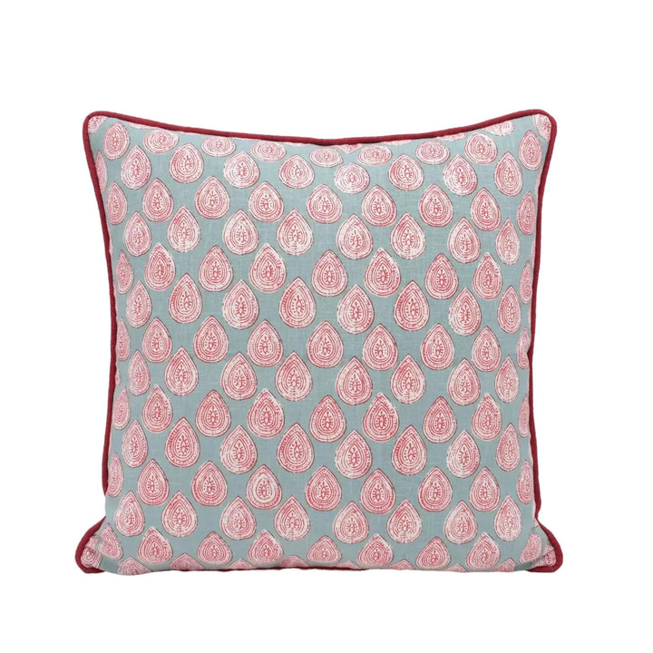 A square throw pillow with a repeating pattern of red and white teardrop shapes on a light blue background.