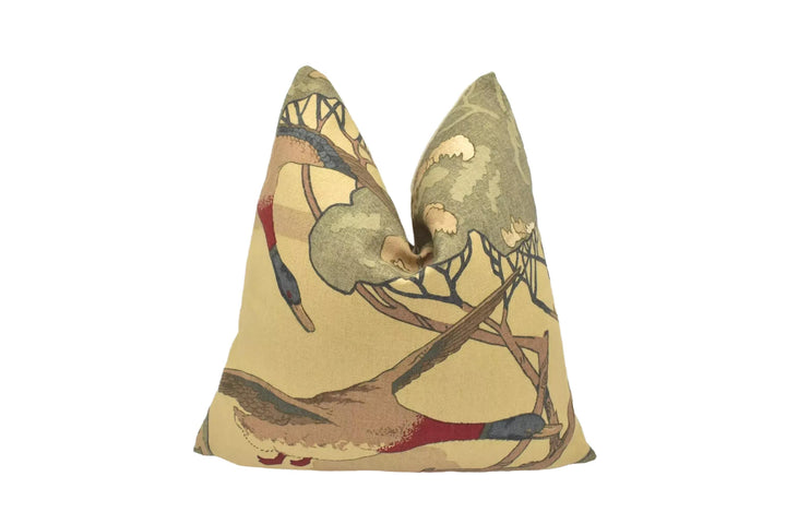 a decorative pillow with a bird design, including ducks and trees, on a white background.