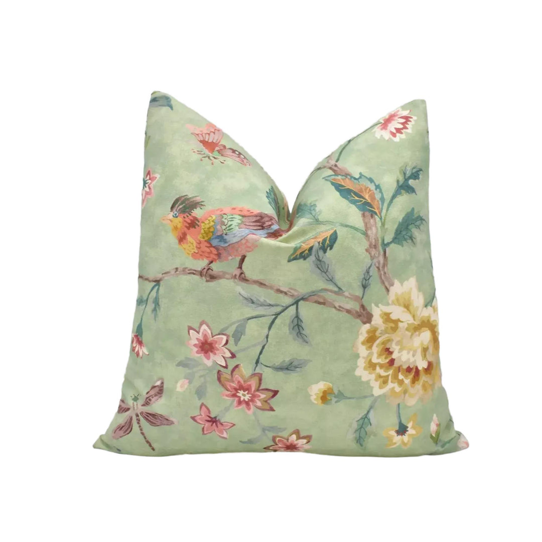 A green throw pillow with a vibrant floral pattern, including a bird perched on a branch and various colorful flowers.