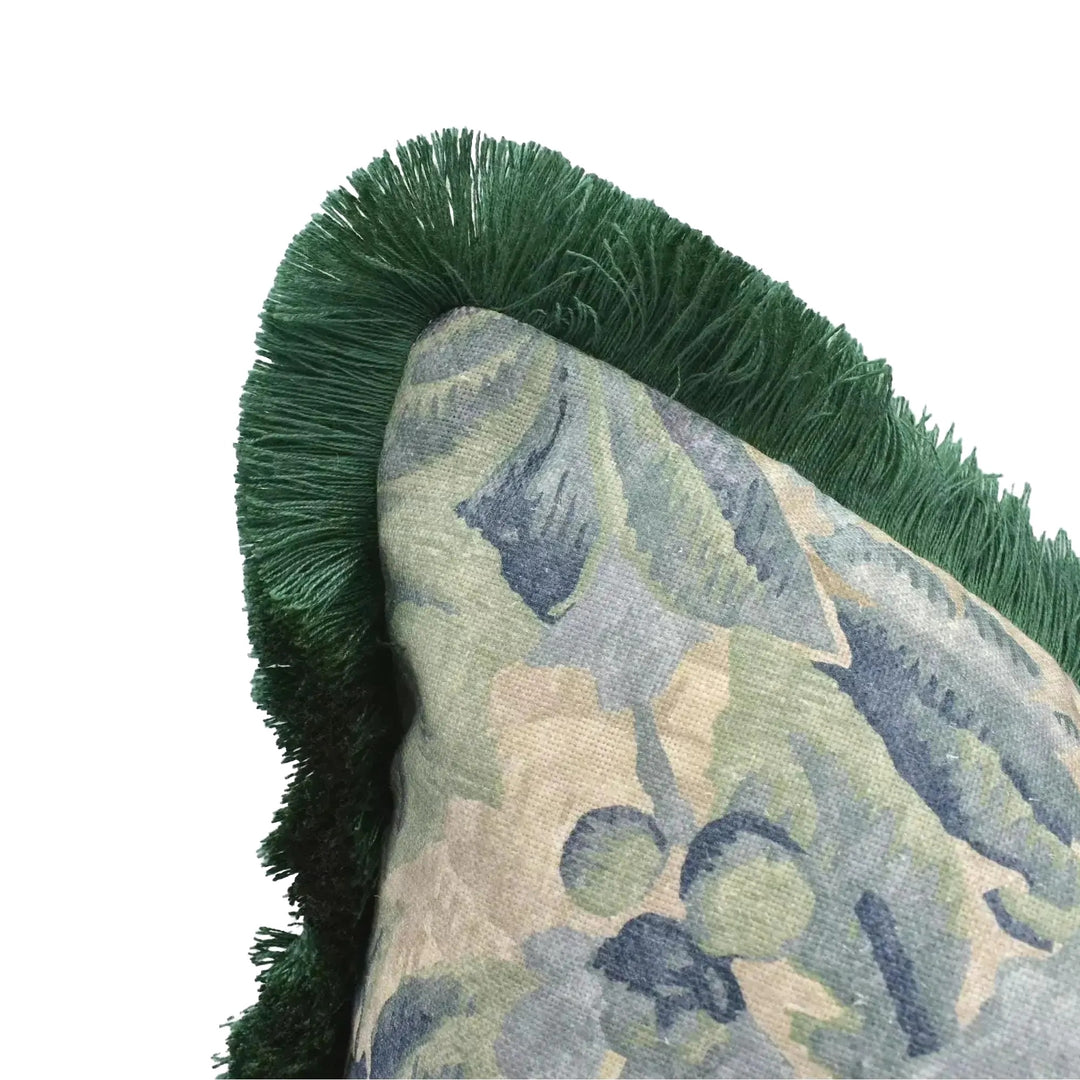 A close-up view of a decorative pillow with a green fringe and a floral pattern.