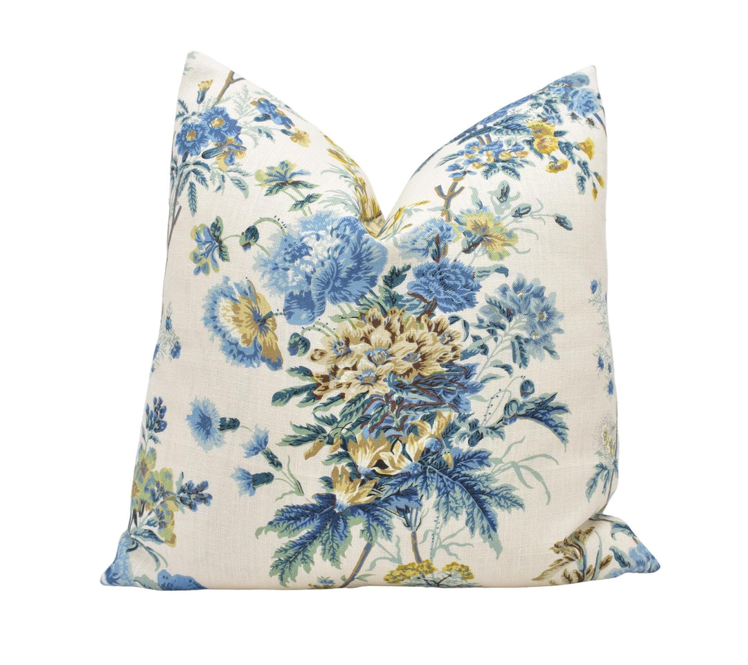 a blue and yellow floral pillow on a white background