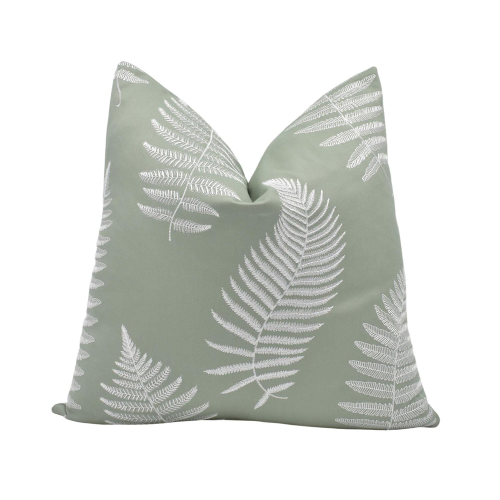a green pillow with white fern leaves printed on it.