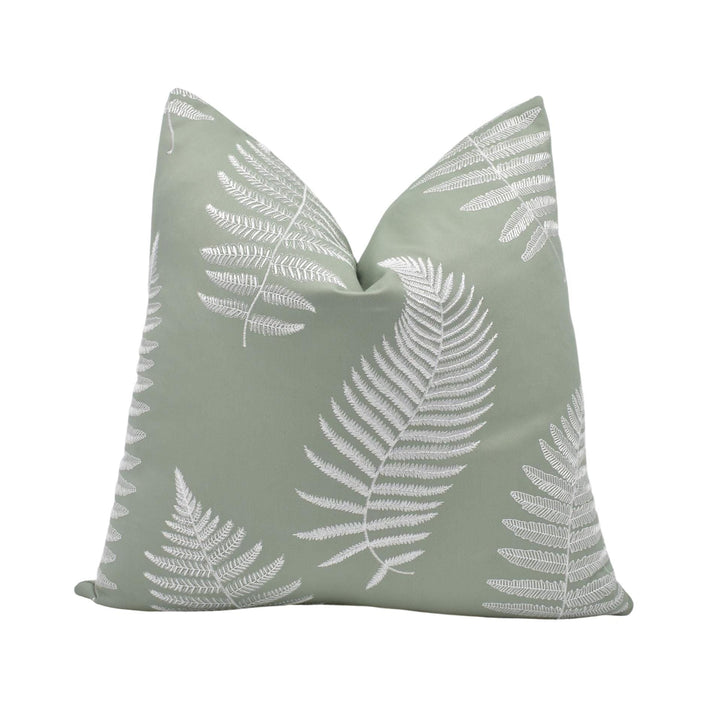 a green pillow with white fern leaves printed on it.