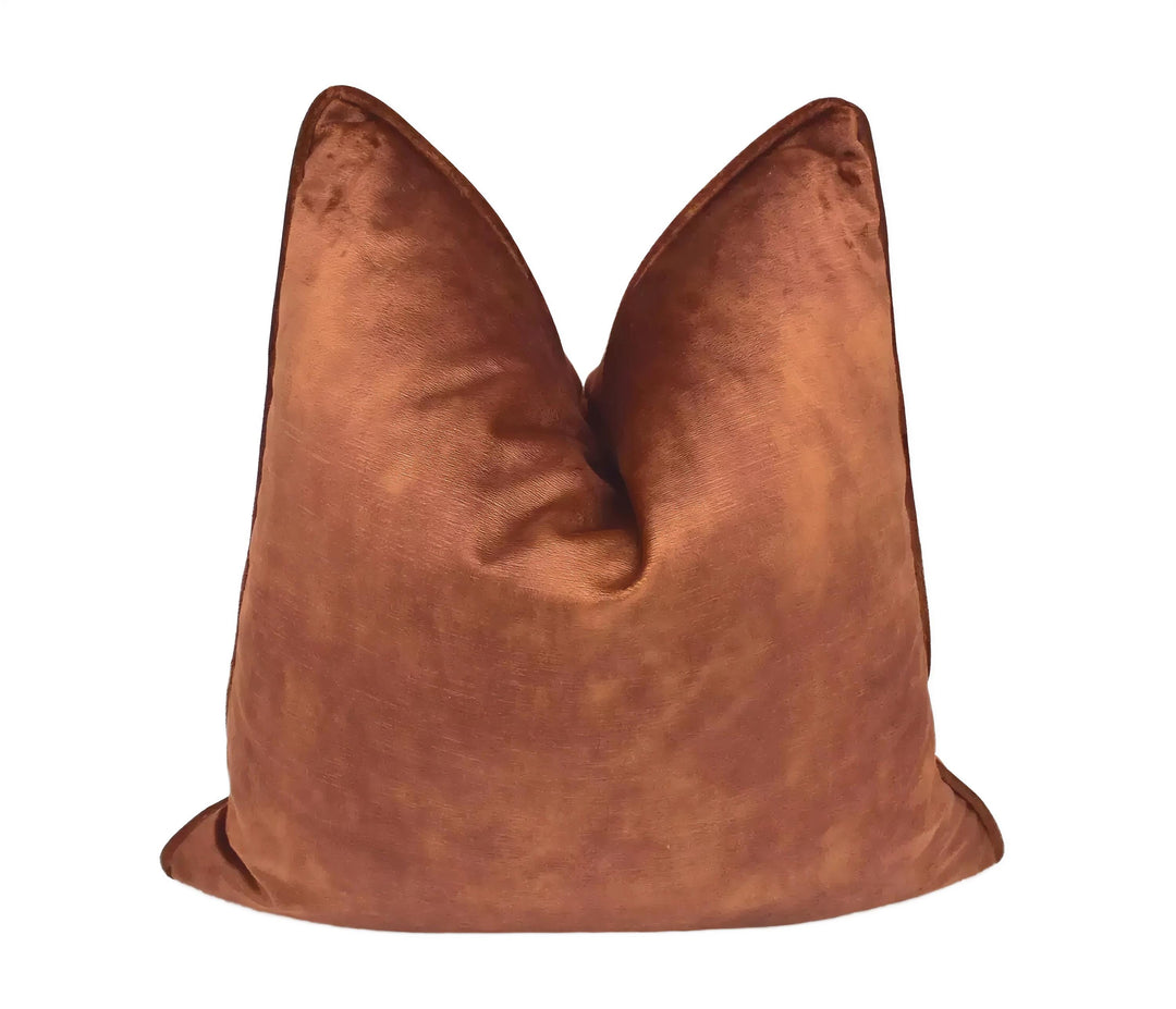 A brown velvet pillow is displayed against a white background.