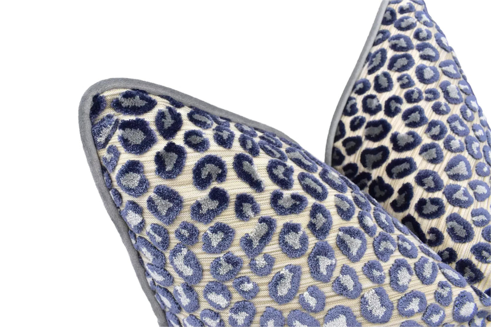 a close-up view of two decorative pillows with a leopard print pattern. The pillows have a textured surface with a repeating pattern of blue and white spots, creating a visually striking and eye-catching design.