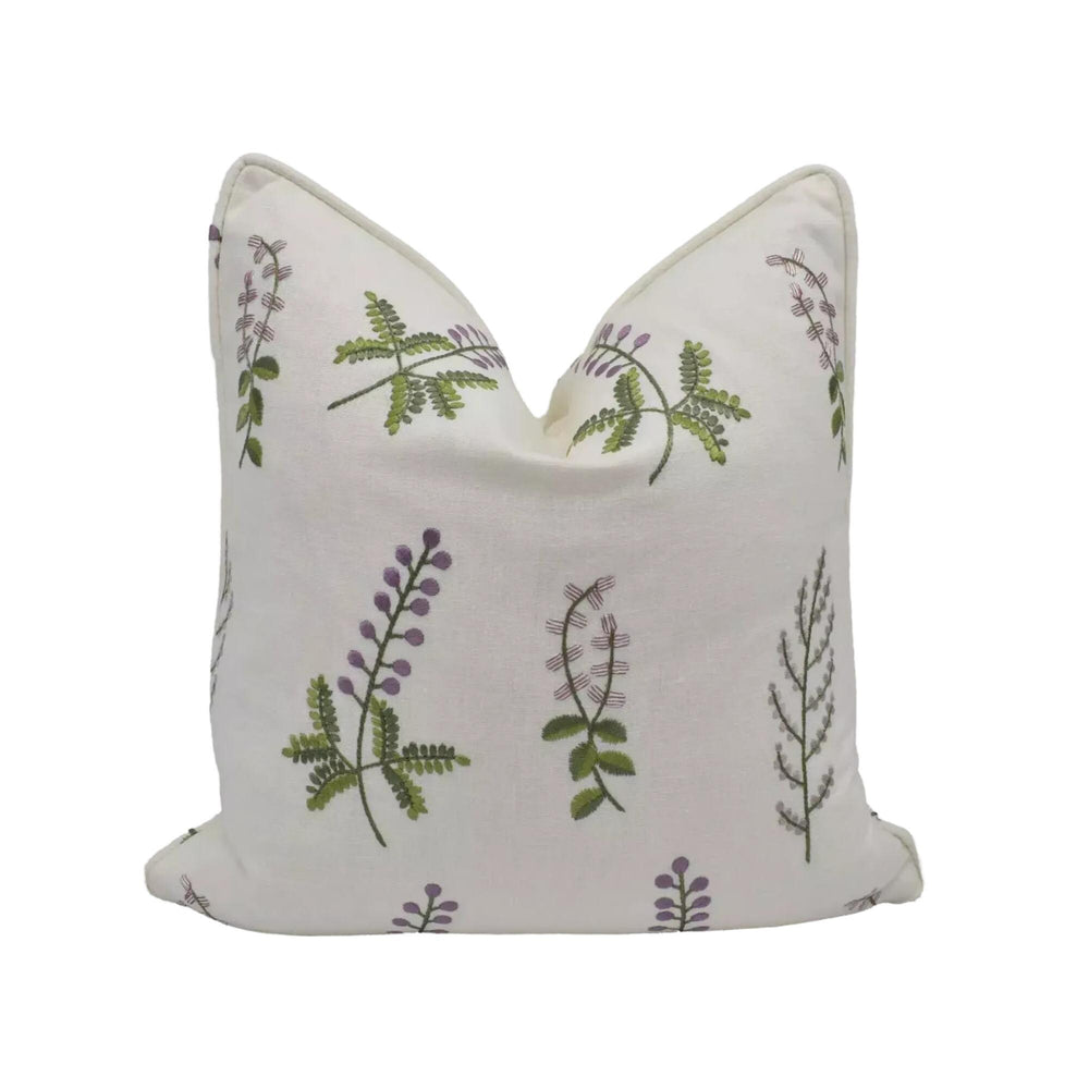 a white pillow with a repeating pattern of green and purple flowers or leaves.