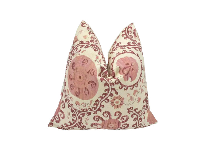 A decorative pillow with a floral pattern in shades of pink and cream.