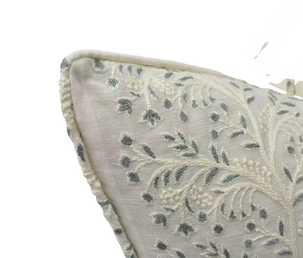A close-up view of a decorative pillow with a floral pattern in shades of white and gray.