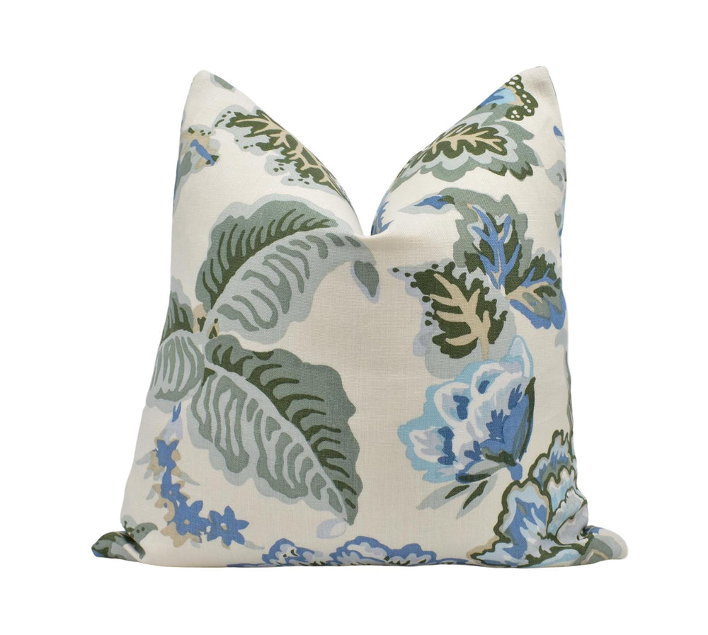 A white pillow with a floral print design in shades of green and blue.