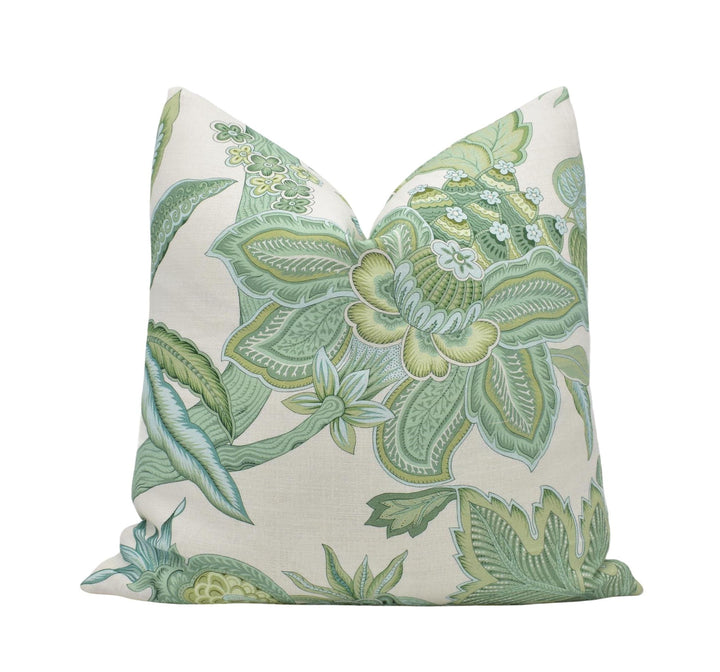 a green and white floral pillow on a white background