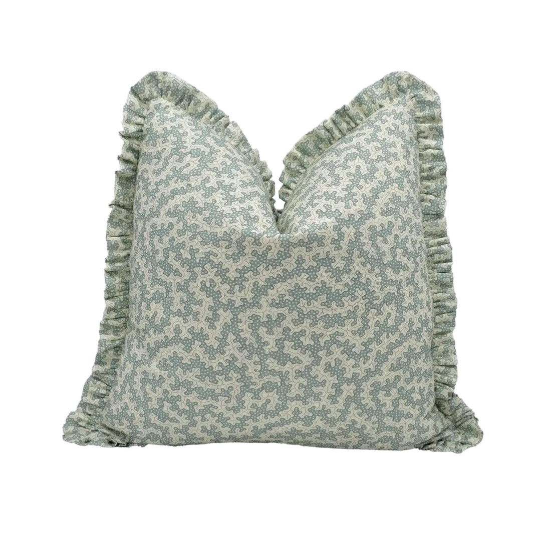 A decorative throw pillow with a floral pattern and ruffled edges.