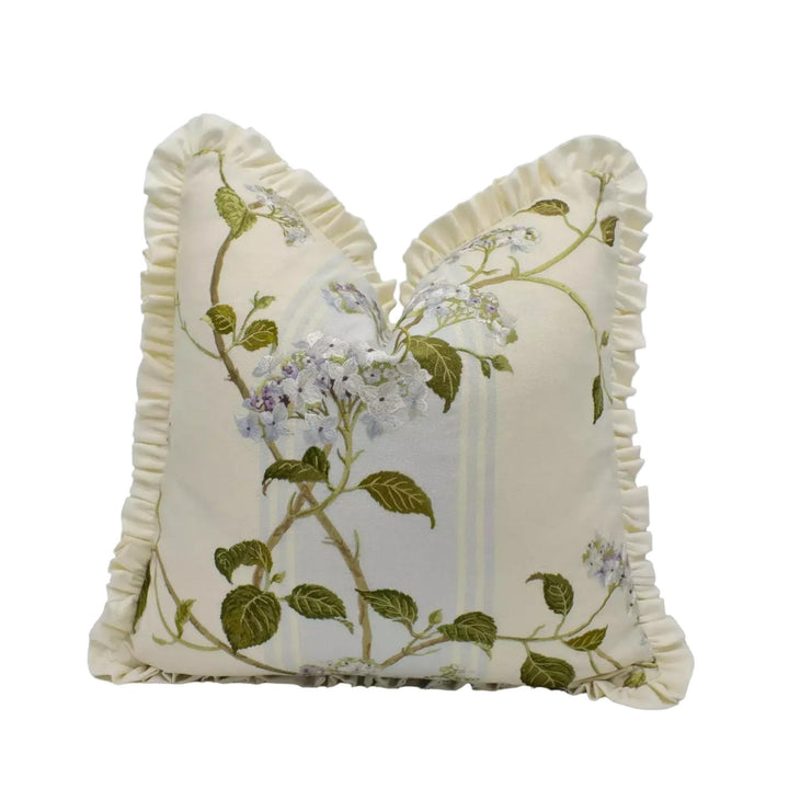 A decorative white pillow with a floral pattern and ruffled edges.