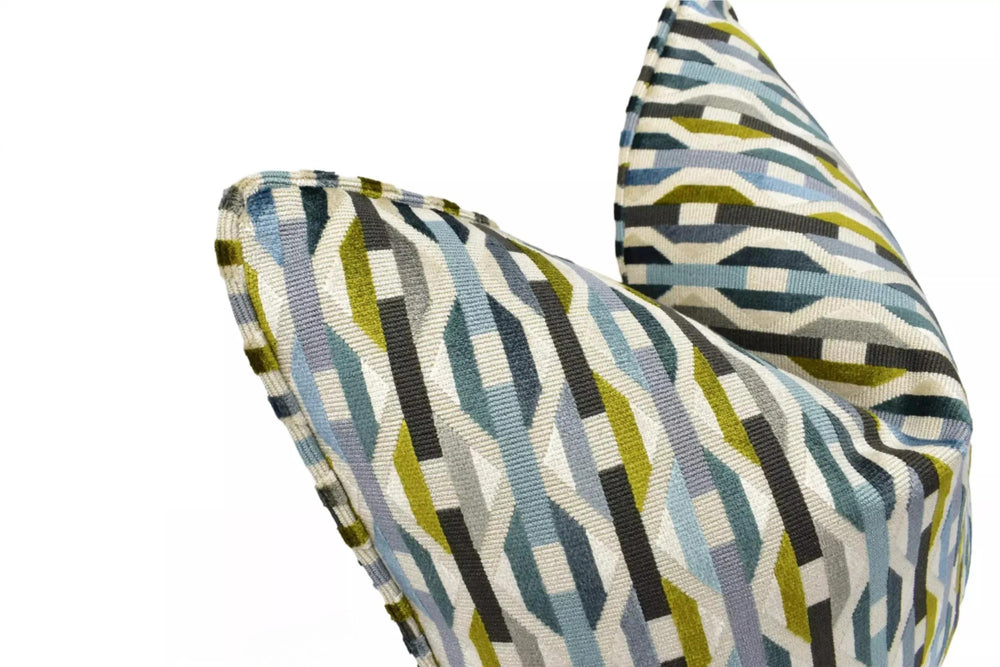 a close-up view of a colorful, geometric-patterned pillow or cushion with a mix of blue, green, and gray colors.