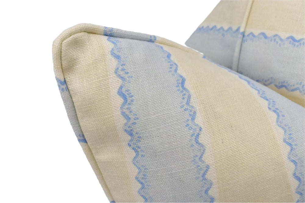 A close-up view of a beige and blue striped pillow, with the fabric pattern and texture visible.