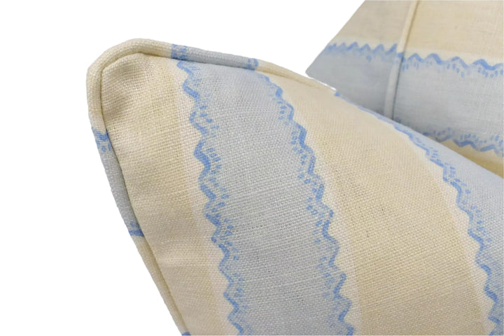 A close-up view of a beige and blue striped pillow, with the fabric pattern and texture visible.