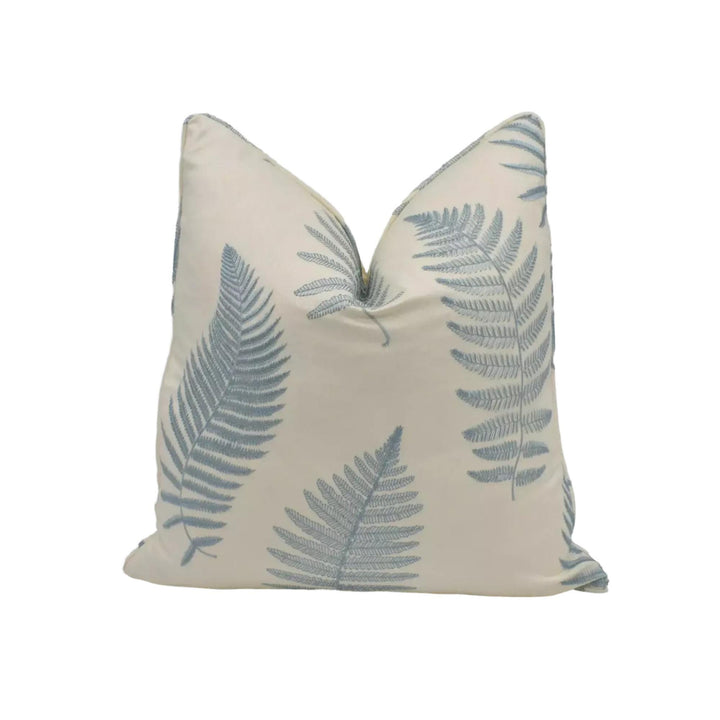 A white pillow with a repeating pattern of blue fern leaves.