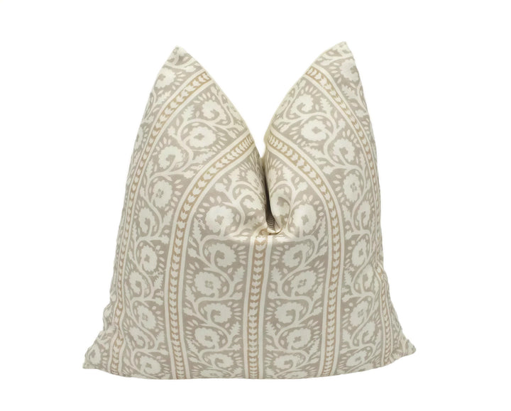 A decorative pillow with a repeating pattern of white and gold floral designs is displayed against a white background.