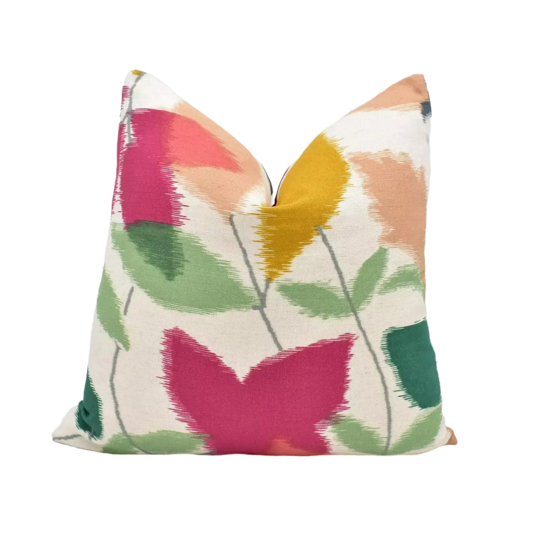 a colorful, abstract floral print pillow with a mix of pink, green, yellow, and orange colors.