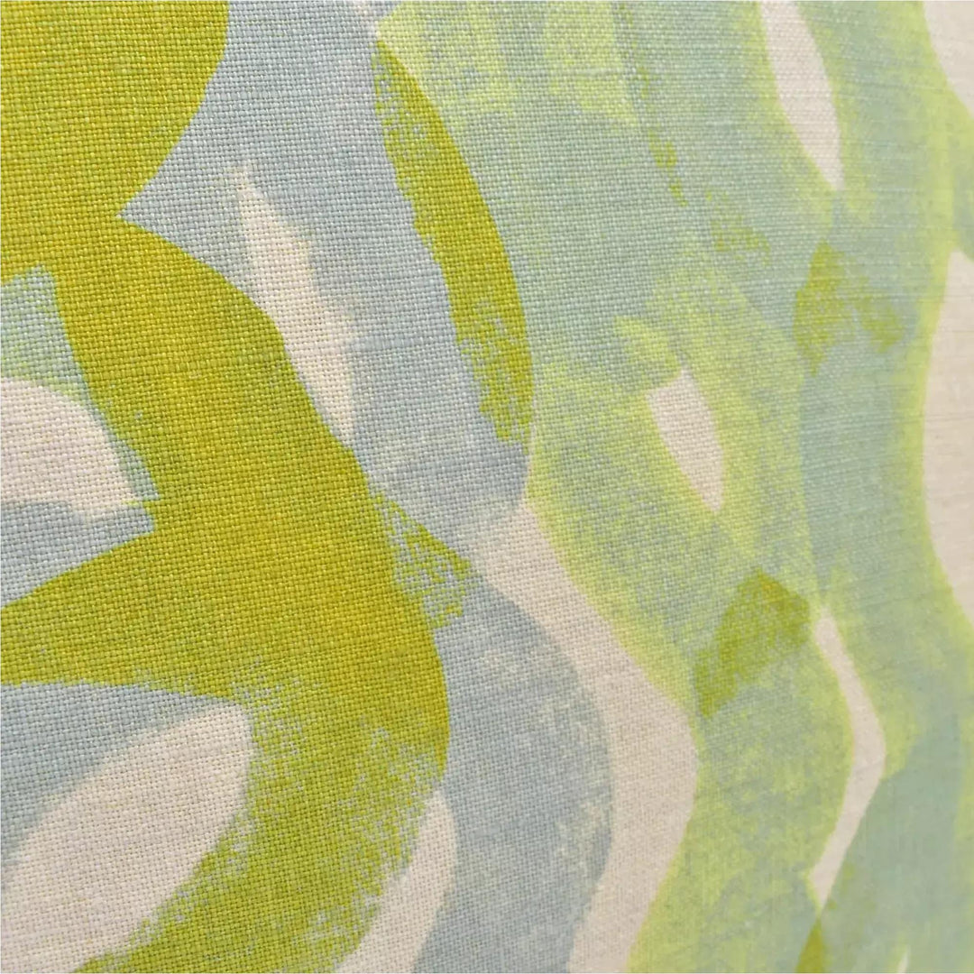 The image is a close-up of a fabric with a vibrant, abstract pattern in shades of green and yellow. The pattern appears to be a mix of brushstrokes and splatters, creating a dynamic and visually interesting design.