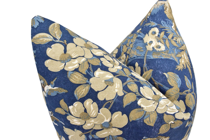 a close-up view of a blue and gold floral patterned pillow, with the flowers and leaves in shades of white and gold.