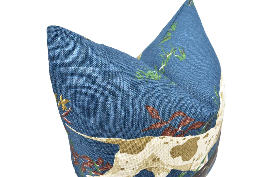 A close-up image of a blue fabric with a pattern of green and brown flowers and leaves, resembling a dog&