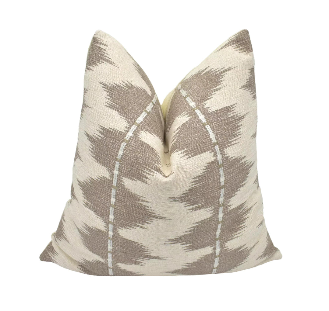 a decorative pillow with a zigzag pattern in shades of brown and beige.