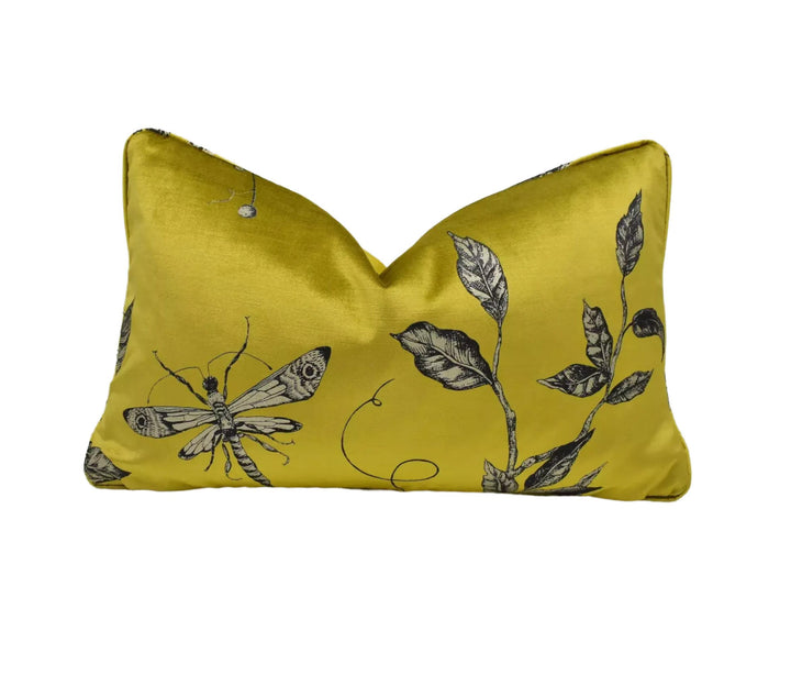 A yellow pillow with a black and white butterfly and leaf design printed on it.