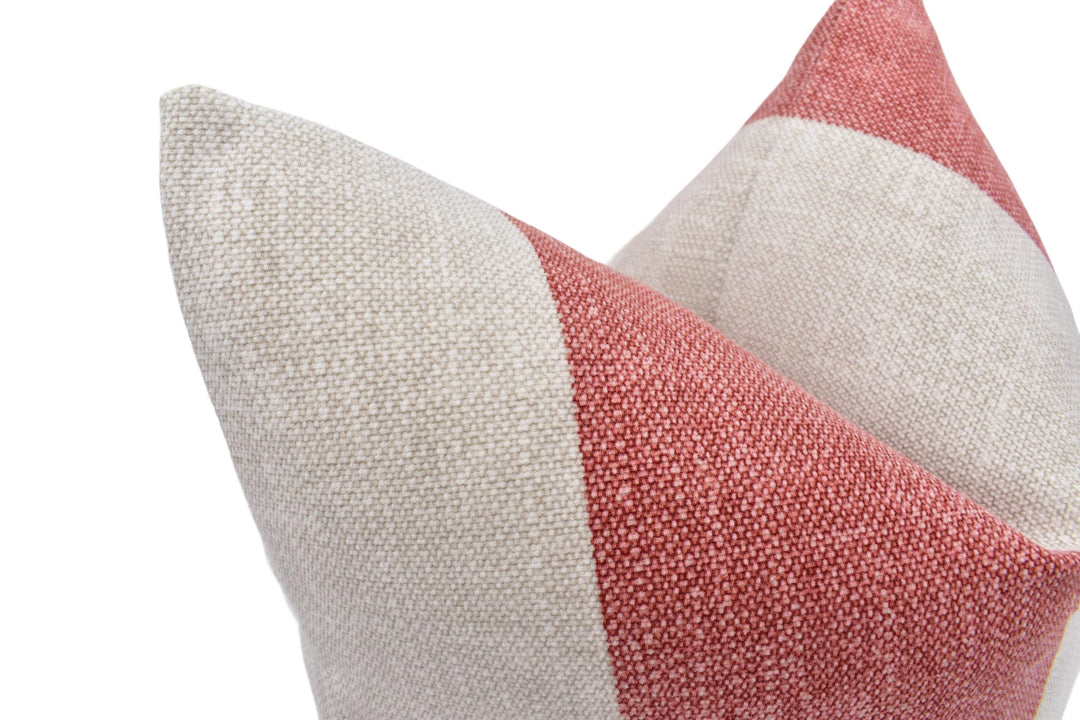 A close-up image of a beige and red fabric, possibly a pillow or cushion, with a textured pattern.