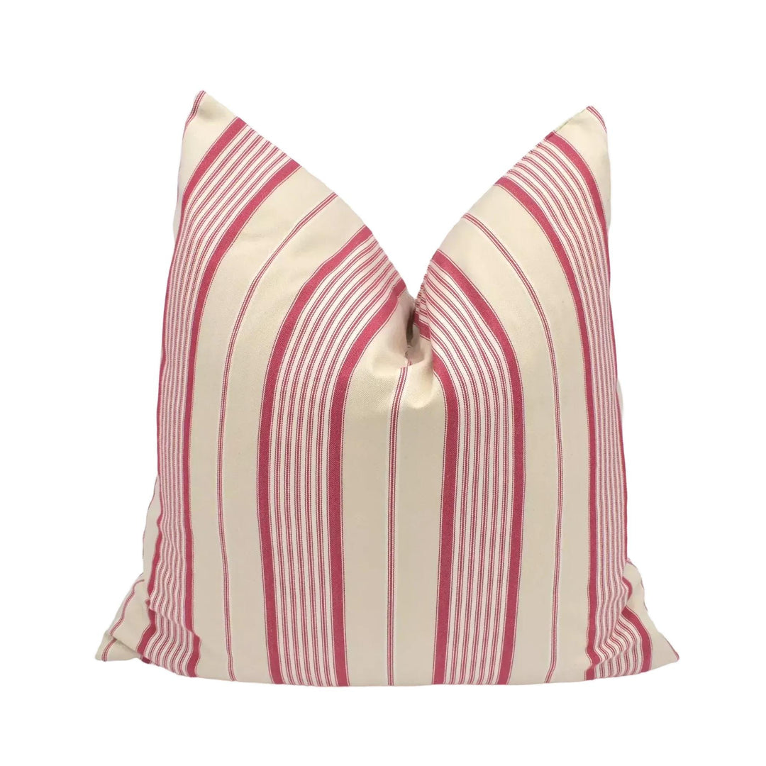 A red and white striped pillow is placed against a white wall.