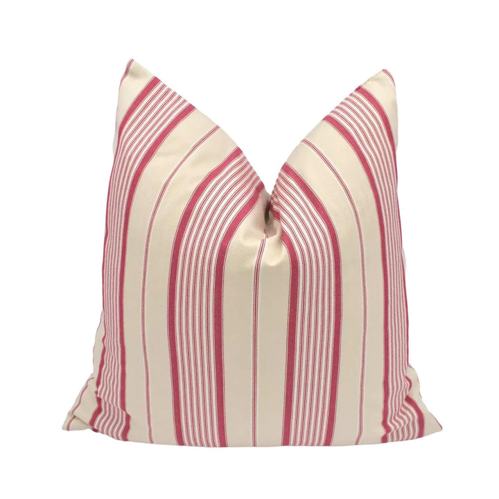 A red and white striped pillow is placed against a white wall.