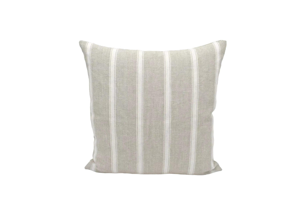 A beige and white striped pillow is placed against a white wall.
